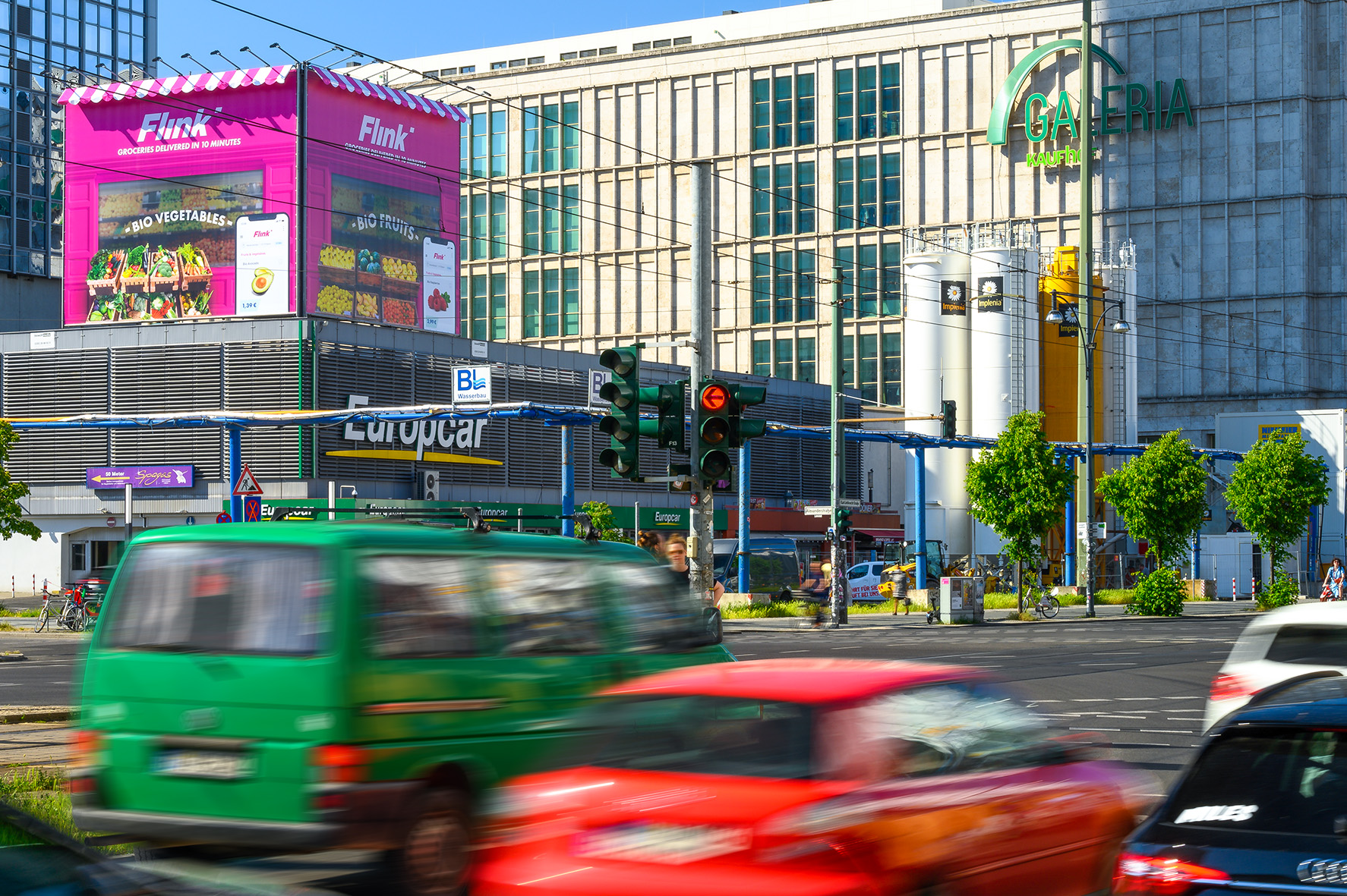 Großformatige Flink-Werbeinstallation im Stil eines übergroßen Kiosks auf einem Berliner Dach, umgeben von stark befahrener Kreuzung und vorbeifahrenden Autos.